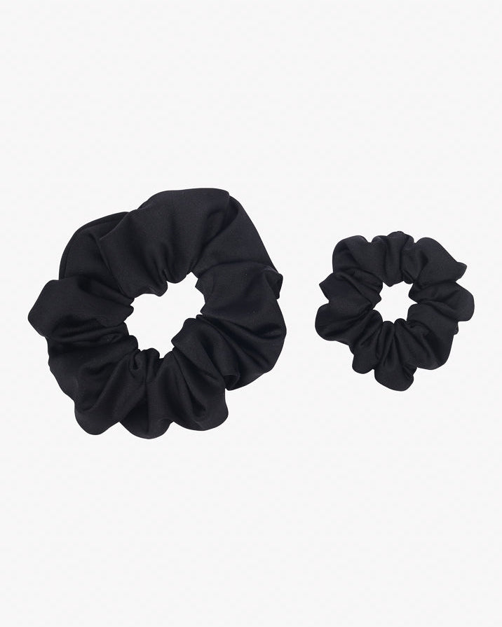 Zwei schwarze Haargummis sind auf weißem Hintergrund abgebildet. Diese aus recyceltem Stoff gefertigten Haargummis haben ein gerüschtes Aussehen. **Main Design’s Haargummi mini** gibt es in zwei Größen, wobei der größere links und der kleinere rechts ist. Perfekt für eine umweltfreundliche Haar-Accessoire-Auswahl.