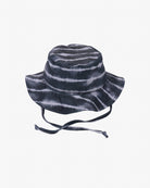 Ein schwarz-weißer Kinder-Sonnenhut im Batik-Design mit breiter Krempe und verstellbaren Kinnriemen. Der Hut hat einen entspannten, lässigen Stil mit einem leicht gewellten Muster und bietet Sonnenschutz UPF 50+. Der Hintergrund ist schlicht weiß.