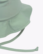 Eine Nahaufnahme eines hellgrünen Kinder-Sonnenhuts von Main Design mit genähter Krempe und verstellbarem Kinnriemen. Das Material, vermutlich umweltfreundlicher Stoff, wirkt glatt und langlebig. Mit einem LSF von 50+ ist er perfekt als Sonnenschutz geeignet. Der schlichte weiße Hintergrund hebt die Details und die Farbe des Huts hervor.