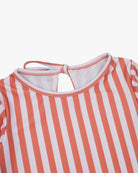 Nahaufnahme des Laila Mädchen Badeanzugs von Main Design mit vertikalen orange-weißen Streifen, rundem Ausschnitt und schlüssellochförmigem Rückenausschnitt mit schmaler Schleife. Der glatte, leicht dehnbare Stoff ist nachhaltig und bietet Sonnenschutzfaktor 50+.