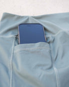 In den versteckten Seitentaschen der hellblauen „Aura Bike Shorts“ von Main Design, die sich durch einen mittelhohen Bund und aufwendige Nähte auszeichnen, steckt teilweise ein Smartphone.