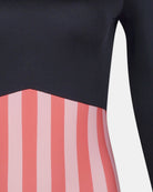 Nahaufnahme des Eclipse Surf Suit von Main Design, der ein schwarzes Oberteil und eine rosa/rot gestreifte untere Hälfte zeigt. Er ist aus nachhaltigem Material gefertigt, hat lange Ärmel und einen scharfen geometrischen Übergang zwischen den Mustern.