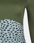 Nahaufnahme des Main Design Eclipse Surf Suit, hergestellt aus nachhaltigem Material. Er besteht aus einem olivgrünen Oberteil und einem Unterteil mit weißem und unregelmäßigem schwarzem Tierprint, sowie einem Teil eines langen Ärmels.