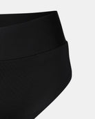 Nahaufnahme der Alice Bikini Hose von Main Design in Schwarz, hergestellt aus recycelten Materialien. Mit glattem, nahtlosem Stoff und breitem Bund, vor einem schlichten hellgrauen Hintergrund.