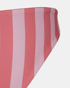 Nahaufnahme der Luxe Bikini Hose von Main Design aus nachhaltig hergestelltem Stoff mit kräftigen vertikalen Streifen in Rosa und Hellrot und einem geschwungenen brasilianischen Schnitt auf weißem Hintergrund.