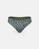 Die Luxe Bikini Hose von Main Design hat eine hohe Taille, eine hellgraue Basis mit unregelmäßigen schwarzen Punkten, ein olivgrünes Innenfutter und einen brasilianischen Schnitt. Sie ist aus recycelten Materialien hergestellt und präsentiert sich auf einem schlichten weißen Hintergrund.