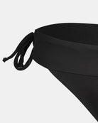 Nahaufnahme der Serene Surf Bikini Hose von Main Design in Schwarz mit seitlichem Bindeband, hergestellt aus recycelten Materialien und chlorbeständigem Stoff, dargestellt vor einem einfarbig weißen Hintergrund.