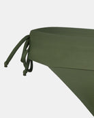 Nahaufnahme der Serene Surf Bikini Hose von Main Design in Olivgrün, hergestellt aus chlorresistentem Stoff mit recycelten Materialien. Das Bild zeigt einen Teil des Bunds und ein verstellbares Seitenband vor einem schlichten weißen Hintergrund.