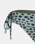 Nahaufnahme der Serene Surf Bikini Hose von Main Design mit abstraktem schwarz-weißem Tupfenmuster, locker geknotetem Seitenband und olivgrünem Futter aus recyceltem Material. Chlorbeständig.