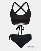 Ein schwarzes Bikini-Set mit einem Oberteil mit überkreuzten Trägern, einem Bindeband auf der Vorderseite und einer hochtaillierten Tide Surf Bikini Hose von Main Design mit frecher Bedeckung und einem verstellbaren Kordelzug in der Taille. Text: "Better together Charm Top | Tide Bottom".