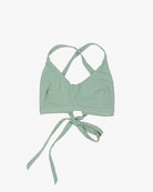 Ein hellgrünes Charm Surf Bikini Oberteil von Main Design mit überkreuzten Trägern auf der Rückseite und einem Bindeverschluss vorne. Das Bralette aus umweltfreundlichem Stoff liegt flach auf einem weißen Hintergrund.