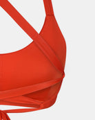 Nahaufnahme des orangefarbenen Charm Surf Bikini Oberteils von Main Design auf Weiß, mit detaillierten Nähten und überlappenden diagonalen Trägern. UPF 50+ Sonnenschutz sorgt für zusätzlichen Schutz bei all Ihren Wassersport Bikini Aktivitäten.