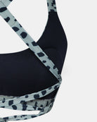 Nahaufnahme des Charm Surf Bikini-Oberteils von Main Design in Schwarz mit hellblauen und schwarzen Animal-Print-Kreuzträgern. Hergestellt aus chlorresistentem Stoff mit UPF 50+ Sonnenschutz. Weißer Hintergrund.