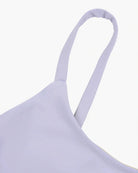 Nahaufnahme eines hellen lavendelfarbenen Spaghettiträgers an einem Sassy Bikini Oberteil Reversibel von Main Design vor einem schlichten weißen Hintergrund. Der aus nachhaltigen Materialien gefertigte Stoff wirkt glatt und leicht dehnbar.