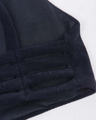 Nahaufnahme eines schwarzen Stoffes mit Netzüberzug und dicken Trägern in Gittermuster vom Sassy Bikini-Top von Main Design. Es wurde aus recycelten Materialien für strukturierte Elastizität gefertigt und bietet eine nahtlose Passform, die sich ideal für Sportbekleidung oder als Teil des Bikini-Oberteils eignet.