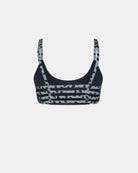 Das Main Design Sassy Bikini-Top ist ein marineblauer Sport-BH mit hellgrauen, unregelmäßig gepunkteten und gestreiften Mustern auf den Trägern und der Vorderseite, die auf einem einfarbig weißen Hintergrund dargestellt sind.