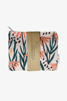 Eine handgefertigte Bikinitasche aus gefaltetem Stoff von Several Needs by Main Design mit einem Blumenmuster aus orangefarbenen Blumen und grünen Blättern. Sie ist in ein braunes Papierband mit der Aufschrift „Eine Bikinitasche zum Reisen“ eingewickelt und bietet sowohl Stil als auch Wasserfestigkeit für Ihre Reisen.