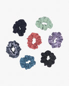 Eine Kollektion von sieben Haargummis im Miniformat aus recyceltem Stoff, die kreisförmig auf weißem Hintergrund angeordnet sind. Die umweltfreundlichen Haargummis von Main Design sind in verschiedenen Farben und Mustern erhältlich, darunter Marineblau, Mintgrün, Koralle, Lavendel, Batik, Blaugrün und Schwarz.