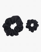 Zwei schwarze Haargummis sind auf weißem Hintergrund abgebildet. Diese aus recyceltem Stoff gefertigten Haargummis haben ein gerüschtes Aussehen. **Main Design’s Haargummi mini** gibt es in zwei Größen, wobei der größere links und der kleinere rechts ist. Perfekt für eine umweltfreundliche Haar-Accessoire-Auswahl.