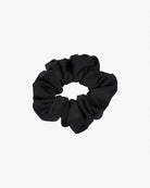 Das Haargummi Mini von Main Design ist ein schwarzes Stoff-Haargummi aus recyceltem Material mit einer gerafften, gekräuselten Textur und in kreisförmiger Form auf schlichtem weißem Hintergrund.