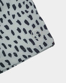 Main Design Lean Boardshorts für Jungen: Weiße Boardshorts mit unregelmäßigen schwarzen Flecken, kleinem rundem Berg-Logo am Saum, abstraktem Animal Print, schnell trocknend und UPF 50+ Sonnenschutz.