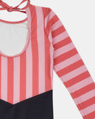 Eine Nahaufnahme des Main Design Kaia Mädchen Badeanzugs mit vertikalen rosa und korallenroten Streifen, Rundhalsausschnitt mit Bindeband im Rücken, UPF 50+ Sonnenschutz und einfarbig schwarzem Unterteil für einen stilvollen Badelook.