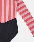 Eine Nahaufnahme des Main Design Kaia Mädchen Badeanzugs zeigt pinke und rote vertikale Streifen auf dem Oberkörper und den Ärmeln, ein unifarbenes schwarzes Unterteil, UPF 50+ Sonnenschutz, wobei nur die rechte Seite des Badeanzugs auf dem Bild zu sehen ist.