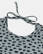 Nahaufnahme des Kaia Mädchen Badeanzugs von Main Design in Hellgrau mit schwarzem Tierprint, mit Rundhalsausschnitt, Bindebandverschluss im Rücken und UPF 50+ Sonnenschutz für zusätzlichen Schutz.