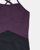 Nahaufnahme des Lena Mädchen Badeanzugs von Main Design: ein ärmelloser Badeanzug aus recycelten Materialien, mit überkreuzten Trägern, einem lila Oberteil, einem schwarzen Unterteil und einer diagonalen Naht, die die beiden Teile trennt.