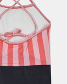 Die Nahaufnahme des Lena Mädchen Badeanzugs von Main Design zeigt rosa und rote Längsstreifen auf dem Oberteil, ein rosa Kreuzband auf dem Rücken und ein unifarbenes dunkles Unterteil, wobei der Schwerpunkt auf dem nachhaltig hergestellten Oberteil liegt.