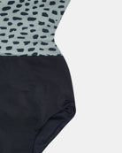 Eine Nahaufnahme des Main Design Milly Mädchen Badeanzugs mit einem hellblauen Oberteil mit schwarzen abstrakten Punkten und einem einfarbig schwarzen Unterteil vor einem einfarbig weißen Hintergrund.