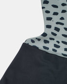 Nahaufnahme des Milly Mädchen Badeanzugs von Main Design: schwarz-weißes, unregelmäßiges Fleckenmuster, das in einfarbiges Schwarz übergeht, mit UPF50-Schutz - stylische Kinderbademode aus der Schweiz.