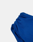 Eine Nahaufnahme des leuchtend blauen Stoffes des Main Design Nalu Mädchen Bikini, der sanfte Falten und eine glatte Struktur auf weißem Grund zeigt - fachmännisch hergestellt aus recycelten Materialien für Stil und Nachhaltigkeit.