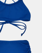 Eine Nahaufnahme des Nalu Mädchen Bikini von Main Design, hergestellt aus recycelten Materialien, mit einem Oberteil im Neckholder-Stil mit Bindeband im Rücken und einer Hose mit hoher Taille, dargestellt auf einem schlichten weißen Hintergrund.