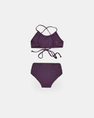 Der Nalu Mädchen Bikini von Main Design in dunklem Lila besteht aus recycelten Materialien, hat ein Halter-Neck-Top mit gekreuzten Trägern und Rückenbindung sowie High-Waist-Bottoms mit UPF 50+ Sonnenschutz auf weißem Hintergrund.