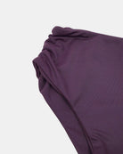 Nahaufnahme des Nalu Mädchen Bikini von Main Design, hergestellt aus recycelten Materialien in lila Stoff mit gerafften Details auf einer Seite, dargestellt vor einem einfarbig weißen Hintergrund.