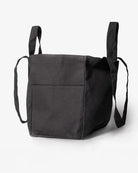 Die Stofftasche klein von OMOM von Main Design ist eine schwarze Bio-Baumwoll-Tote mit kurzen Henkeln, langen Schulterriemen, sichtbarer Fronttasche und minimalistischem Design auf weißem Hintergrund.