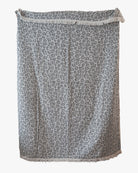 Die Main Design Decke Savanna, eine rechteckige Decke in Grau und Weiß mit Leopardenmuster und Fransen an den Rändern, ist vor einem einfarbig weißen Hintergrund abgebildet.