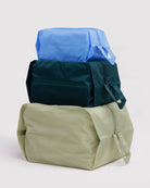 Das BAGGU 3D Zip Set von BAGGU besteht aus drei rechteckigen Reißverschlusstaschen in den Farben groß helloliv, mittel dunkelgrün und klein hellblau - ideal als nachhaltige Taschen für stilvolle Reiseaccessoires.
