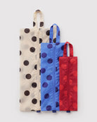Das „BAGGU 3D Zip Set“ von BAGGU umfasst drei aufrecht stehende, rechteckige Beutel aus recyceltem Nylon in den Farben Creme, Blau und Rot mit Punkten, jeweils mit einem Tragegriff oben und einem Reißverschluss in der Mitte – stilvolle Reiseaccessoires in verschiedenen Größen.