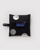 BAGGU Baby Tragetasche in Silver Metallic Polka Dot: Zusammengefaltet im schwarzen Beutel mit silbernen Punkten.