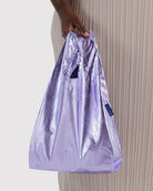 BAGGU Baby Tragetasche in Lavender Metallic: Kleine lavendelfarbene Metallic-Tragetasche an der Hand getragen.