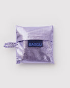 BAGGU Baby Tragetasche in Lavender Metallic: Zusammengefaltet im lavendelfarbenen Metallic-Beutel.