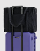 BAGGU Cloud Carry-On Tasche in Black: Rückansicht der schwarzen Reisetasche auf einem Rollkoffer.
