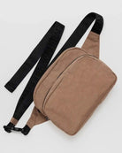 Eine braune BAGGU Gürteltasche aus recyceltem Nylon mit einer großen Reißverschlusstasche und einem schwarzen, verstellbaren, geprägten Riemen liegt flach auf einer hellen Oberfläche.