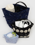 Das BAGGU Go Pouch Set von BAGGU enthält drei Taschen aus recyceltem Nylon: eine große Tasche mit Sternbildaufdruck für Stoff und Kopfhörer, eine mittlere Tasche mit Mondmuster für Kabel und eine kleine Tasche für Glas, Tube und Tupfer.