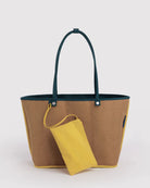 Die „BAGGU Large Nylon Reversible Tote“ von BAGGU besticht durch einen braunen Korpus mit dunkelgrünen Henkeln und gelben Seiteneinsätzen, ergänzt durch ein passendes gelbes Reißverschluss-Täschchen, das an einem der Henkel befestigt ist – dargestellt vor einem schlichten, hellen Hintergrund.