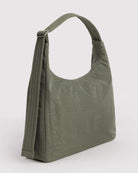 Eine minimalistische BAGGU-Nylon-Umhängetasche in Olivgrün mit einem breiten, gesteppten Riemen und schlichtem Design steht aufrecht vor einem hellen Hintergrund.