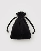 Die BAGGU Pleated Tragetasche von BAGGU aus schwarzem, recyceltem Ripstop-Nylon mit zwei eleganten Ribbon-Ties wird auf einem schlichten, hellgrauen Hintergrund präsentiert.