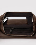 Nahaufnahme des Innenraums der BAGGU Recycled Leather Pochette mit geöffnetem Reißverschluss, die eine Karte in einem Innenfach und ein weiteres Fach mit schwarzem Reißverschluss zeigt - eine stilvolle, minimalistische Tasche aus recyceltem Leder von BAGGU.